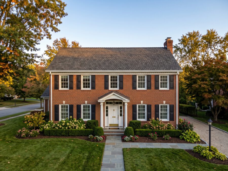 Brick colonial home with a new roof and white seamless gutters